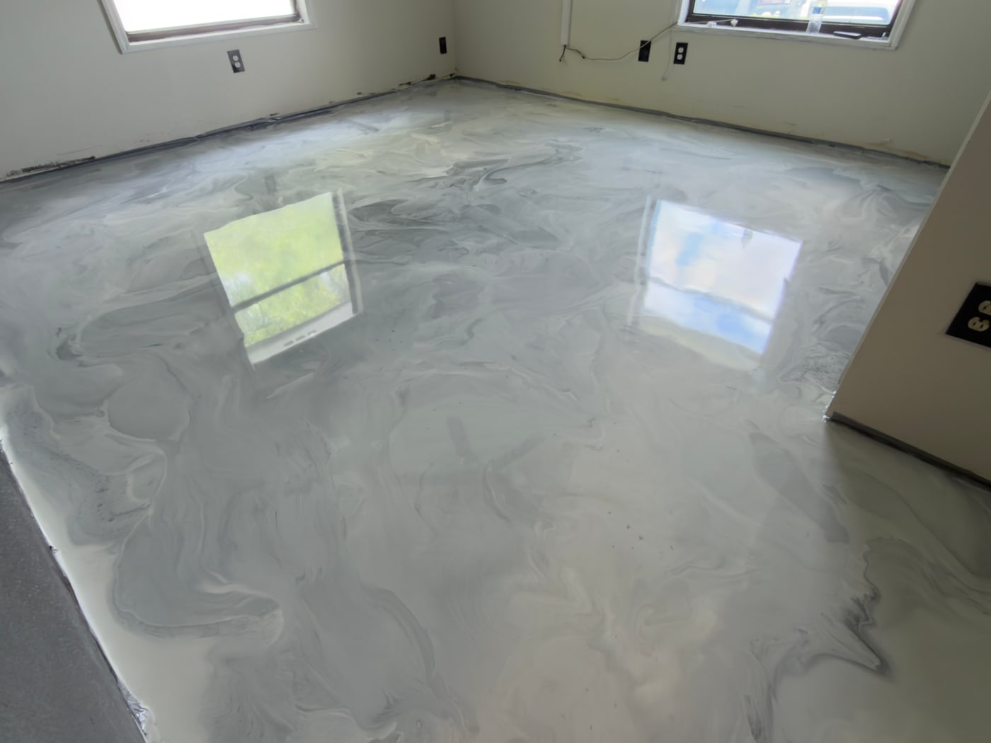 Finished grey metallic epoxy floor reflecting the room's windows